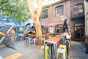 Outside the Loft, a leafy courtyard with stools, tables and a wall mural