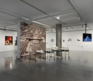 An exhibition in the industrial gallery space with paintings and sculptures